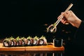 A Salmon Dragon roll in Chinese chopsticks over the dish on the table