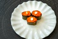 Salmon eggs or Ikura in Japanese style sushi fresh from raw salmon fish served on a white plate on dark background Royalty Free Stock Photo