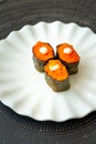 Salmon eggs or Ikura in Japanese style sushi fresh from raw salmon fish served on a white plate on dark background Royalty Free Stock Photo