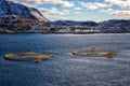 Salmon farm in norwegian fjord, scenic winter landscape with water, mountains and blue sky with clouds, Lofoten Islands, Norway