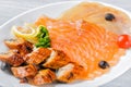 Salmon fillet pieces, conger eel, sturgeon pieces served with lemon, black olives, herbs and cherry tomato on white plate close up Royalty Free Stock Photo