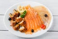 Salmon fillet pieces, conger eel, sturgeon pieces served with lemon, black olives, herbs and cherry tomato on white plate and wood Royalty Free Stock Photo