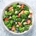 Salmon fish and avocado salad with fresh spinach leaves, broccoli, blueberry dressed with olive oil