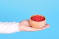 Salmon fish caviar, seafood on wooden jar in hand, isolated on blue background