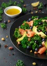 Salmon Kale super food Salad with avocado, pistachio nuts and blueberries on black plate