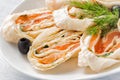 Salmon lavash rolls with dill, cheese and black olives on white plate. Close up image