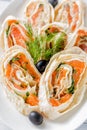 Salmon lavash rolls with dill, cheese and black olives on white plate. Close up image with selective focus