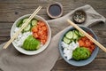 Salmon poke bowl with fresh fish, rice, cucumber, avocado with black and white sesame. Old wooden table. Food concept Royalty Free Stock Photo