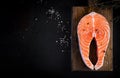 Raw fish salmon steak fillet with cooking ingredients, herbs and lemon on black background with copy space. Royalty Free Stock Photo