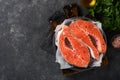 Salmon. Raw salmon steak. Fresh raw salmon fish with cooking ingredients, herbs and lemon prepared for grilled baking on black bac Royalty Free Stock Photo