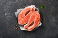 Salmon. Raw salmon steak. Fresh raw salmon fish with cooking ingredients, herbs and lemon prepared for grilled baking on black bac Royalty Free Stock Photo