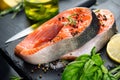 Salmon. Raw trout fish steak with herbs and lemon on black slate background. Cooking, seafood Royalty Free Stock Photo