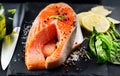 Salmon. Raw trout fish steak with herbs and lemon on black slate background. Cooking, seafood. Healthy eating Royalty Free Stock Photo