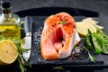 Salmon. Raw trout fish steak with herbs and lemon on black slate background. Cooking, seafood Royalty Free Stock Photo