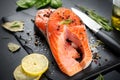 Salmon. Raw trout fish steak with herbs and lemon on black slate background. Cooking, seafood. Healthy eating Royalty Free Stock Photo