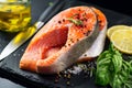 Salmon. Raw trout fish steak with herbs and lemon on black slate background. Cooking, seafood Royalty Free Stock Photo