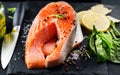 Salmon. Raw trout fish steak with herbs and lemon on black slate background. Cooking, seafood Royalty Free Stock Photo