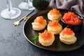 Salmon red caviar toast. Christmas canape or toast with red caviar on black plate on dark background. Idea to xmas snack Royalty Free Stock Photo