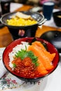 Salmon rice bowl served with ikura salmon roe, crab, seaweed and wasabi with grilled corn and sliced potato at the restaurant. Royalty Free Stock Photo