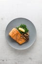 Salmon roast steak. Portion of roast salmon steak spinach mushrooms and lemon on white concrete background Royalty Free Stock Photo