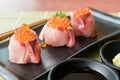 Salmon Roe on Hamachi sushi on black plate along with Japanese sauce and green leaf decoration, Japanese food, close up at sushi Royalty Free Stock Photo