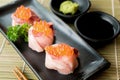 Salmon Roe on Hamachi sushi on black plate along with Japanese sauce and green leaf decoration, Japanese food, close up at sushi Royalty Free Stock Photo