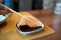 Salmon Sashimi - Hand holding chopsticks to pick fresh salmon and dip into soy sauce with wasabi,l.