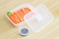 Salmon Sashimi inside a plastic box container ready to serve meal with soy sauce in a plastic cup container. The ready to go salmo