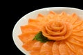 Salmon sashimi serve on flower shape on ice white bowl boat on black isolated background