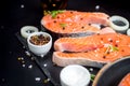 Salmon steak, pepper and salt, herbs on black stone concrete table, copy space top view Royalty Free Stock Photo