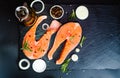 salmon steak, pepper and salt, herbs on black stone concrete table, copy space top view Royalty Free Stock Photo