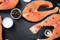 salmon steak, pepper and salt, herbs on black stone concrete table, copy space top view Royalty Free Stock Photo