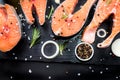 salmon steak, pepper and salt, herbs on black stone concrete table, copy space top view Royalty Free Stock Photo