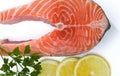 Salmon steak with a sprig of parsley and three lemon slices isolated on white