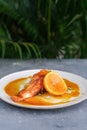 Salmon steak with zucchini noodles with orange sauce and orange on a white plate