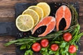 Salmon steakes with greenery, lemon and cherry tomatoes on the black board