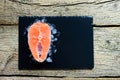 Salmon steaks on ice on black wooden table top view. Fish food concept. Copy space