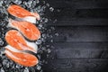 Salmon steaks on ice on black wooden table top view. Fish food concept. Copy space Royalty Free Stock Photo