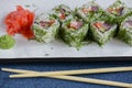 Salmon sushi rolls served on a white plate with ginger and wasabi sauce in a restaurant on table. Japanese cuisine. Royalty Free Stock Photo