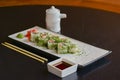 Salmon sushi rolls served on a white plate with ginger and wasabi and soy sauce in a restaurant table. Japanese cuisine. Royalty Free Stock Photo