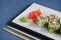 Salmon sushi rolls served on a white plate with ginger and wasabi and soy sauce in a restaurant table. Japanese cuisine. Royalty Free Stock Photo