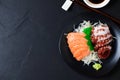 Salmon and Tako sashimi on black dish with chopsticks