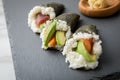 Salmon, tuna fish and Surimi avocado Temaki sushi with pickled ginger and wasabi on slate plate and marble background Royalty Free Stock Photo