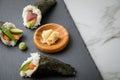 Salmon, tuna fish and Surimi avocado Temaki sushi with pickled ginger and wasabi on slate plate and marble background Royalty Free Stock Photo