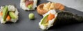 Salmon, tuna fish and Surimi avocado Temaki sushi with pickled ginger and wasabi on slate plate and marble background Royalty Free Stock Photo