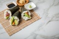 Salmon, tuna fish and Surimi avocado Temaki sushi with soy sauce, pickled ginger and wasabi on mat and marble background Royalty Free Stock Photo