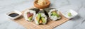 Salmon, tuna fish and Surimi avocado Temaki sushi with soy sauce, pickled ginger and wasabi on mat and marble background Royalty Free Stock Photo