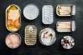 Salmon, tuna, trout mackerel and anchovy - Canned fish in tin cans, on black background, top view flat lay Royalty Free Stock Photo