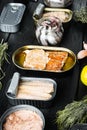 Salmon, tuna, trout mackerel and anchovy - Canned fish in tin cans, on black wooden table background with herbs and ingredients Royalty Free Stock Photo