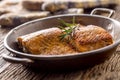Salmon. Two juicy salmon steaks in roast pan with herb decoration on rustic oak table